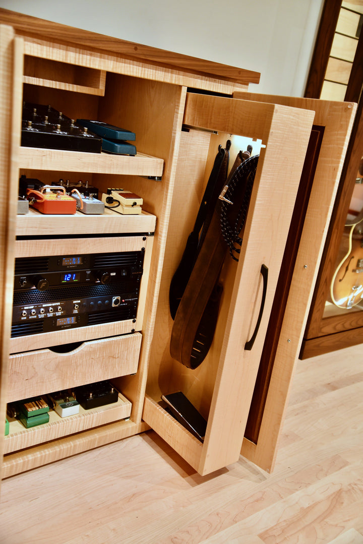 Tall pull-out cubby swung open with guitar straps and cables hung on hooks