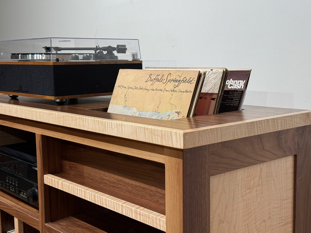 Record Console with a turntable on top and an album cover standing in the slot cut into the walnut surface