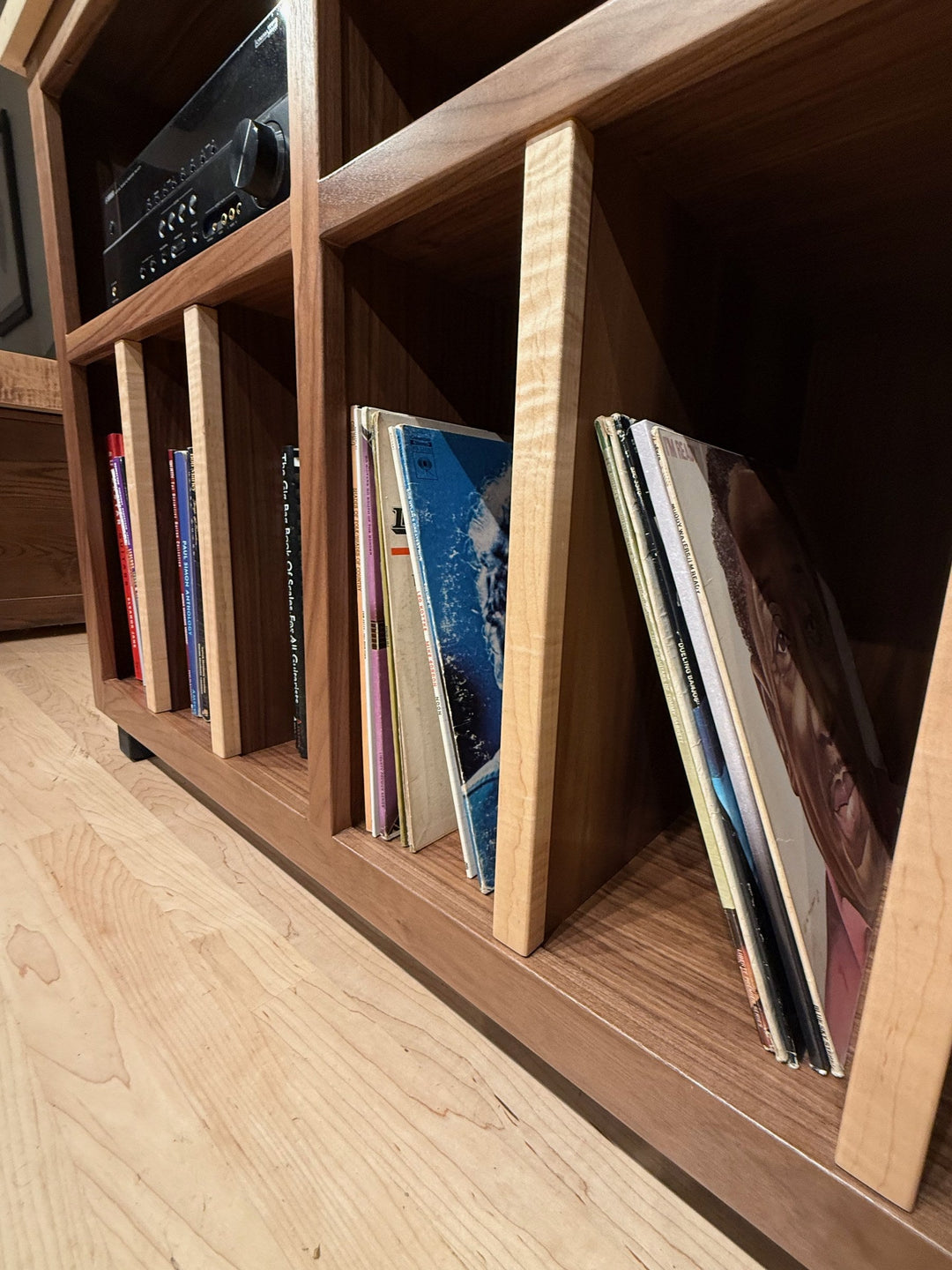 LPs filed upright between solid hardwood dividers in the lower storage bays