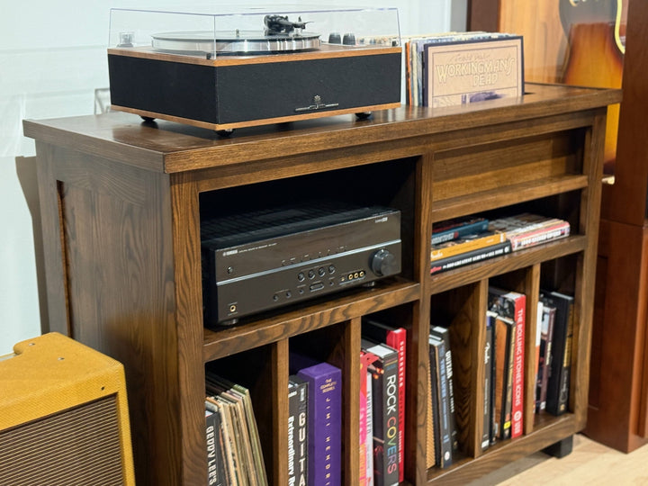 Three quarter view of the ash Record Console in a room with a guitar and amplifier